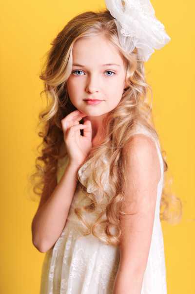 Girl's long blonde curls with a white hair accessory